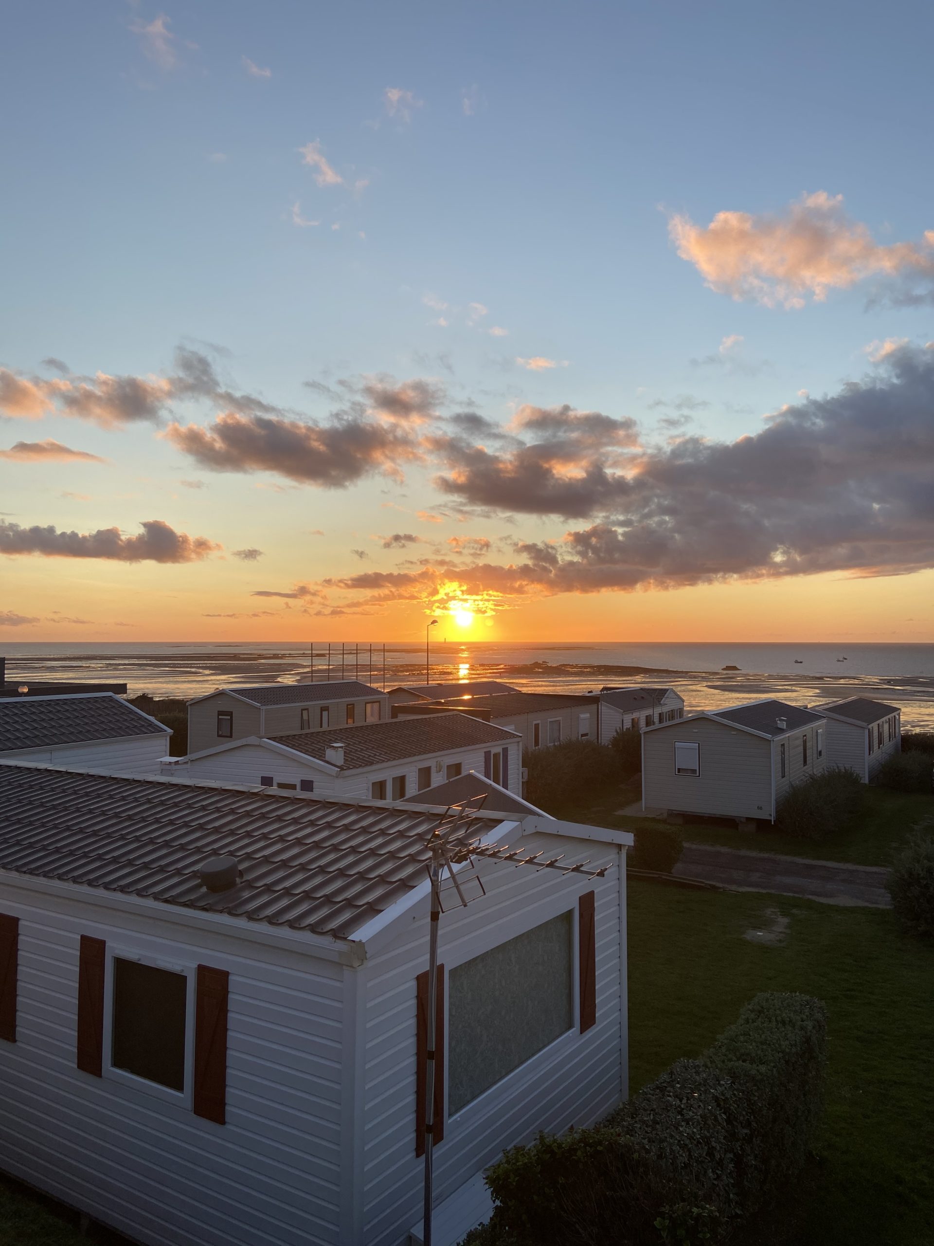 Camping en Normandie avec vue sur un couché de soleil en bord de mer.